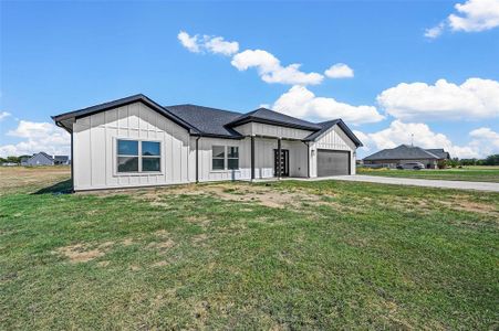 View of front of property featuring a garage and a front lawn