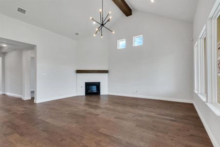 Unfurnished living room featuring beam ceiling, dark wood-type flooring, a chandelier, and high vaulted ceiling