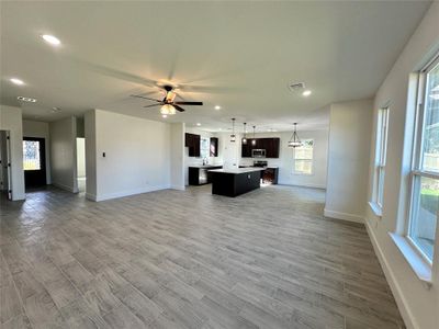 Unfurnished living room featuring ceiling fan, sink, light hardwood / wood-style floors, and a healthy amount of sunlight