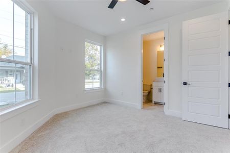 Unfurnished bedroom featuring ceiling fan, light carpet, and connected bathroom