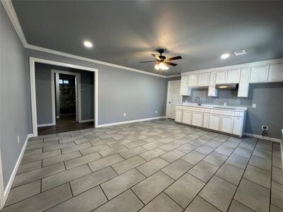 Kitchen featuring crown molding, sink, white cabinets, and ceiling fan