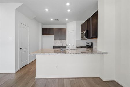 This spacious kitchen features high ceilings, stained wood cabinets, granite countertops, SS appliances, modern tile backsplash, recessed lighting, extended countertop for breakfast bar, and pantry all overlooking your huge family room.