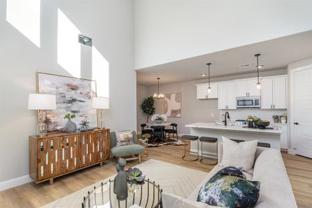 Living room with a high ceiling, light wood-type flooring, an inviting chandelier, and sink