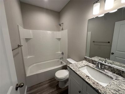 Full bathroom featuring hardwood / wood-style floors, vanity,  shower combination, and toilet