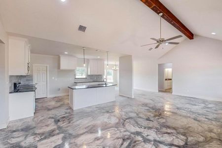 Kitchen featuring white cabinets, ceiling fan with notable chandelier, beamed ceiling, and a center island