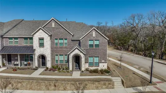 Townhome / multi-family property featuring a standing seam roof, covered porch, stone siding, brick siding, and metal roof