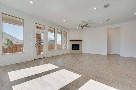 Unfurnished living room with ceiling fan, light hardwood / wood-style floors, and a high end fireplace