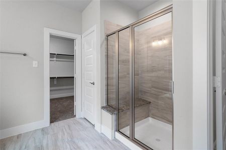 This primary bathroom is definitely move-in ready! Featuring a framed walk-in shower with tile surround, separate garden tub for soaking after a long day with custom tile detailing, grey cabinets with light countertops, spacious walk-in closet with shelving, high ceilings, custom paint, sleek and modern finishes.