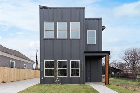 Rear view of property with board and batten siding, fence, and a lawn