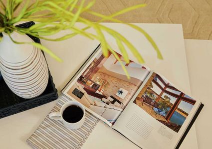 Staged living room with coffee table, cup of coffee, and open book.