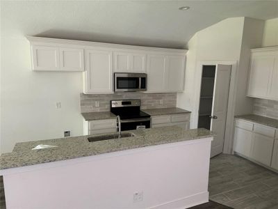 Kitchen featuring sink, decorative backsplash, white cabinetry, and stainless steel appliances