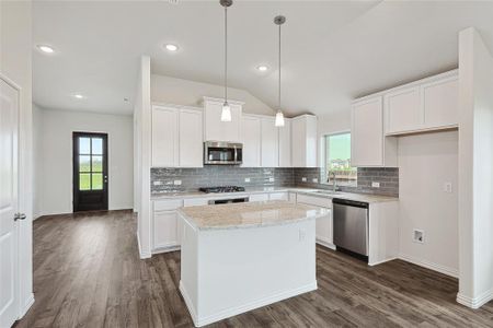 Kitchen featuring appliances with stainless steel finishes, white cabinetry, vaulted ceiling, dark wood-type flooring, and a center island