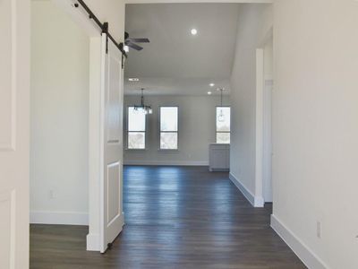 Corridor with a barn door, an inviting chandelier, and dark wood-type flooring