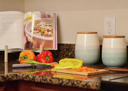 Trace kitchen with white jars, fresh vegetables, and open cook book