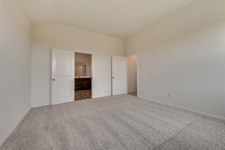 Unfurnished bedroom featuring carpet flooring, lofted ceiling, and connected bathroom