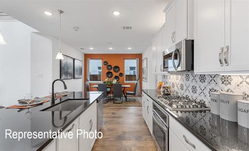 Kitchen with sink, dark wood-type flooring, decorative light fixtures, white cabinets, and appliances with stainless steel finishes