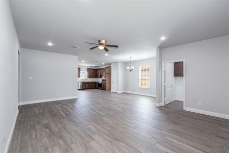 Unfurnished living room featuring recessed lighting, visible vents, wood finished floors, and ceiling fan with notable chandelier