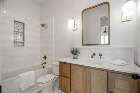 Full bathroom featuring tiled shower / bath combo, vanity, and toilet