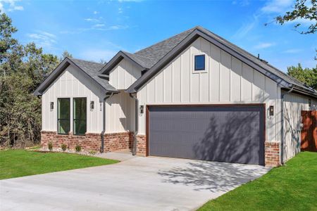 Modern inspired farmhouse featuring a garage and a front yard