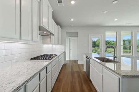 Kitchen with appliances with stainless steel finishes, sink, white cabinetry, and dark hardwood / wood-style floors