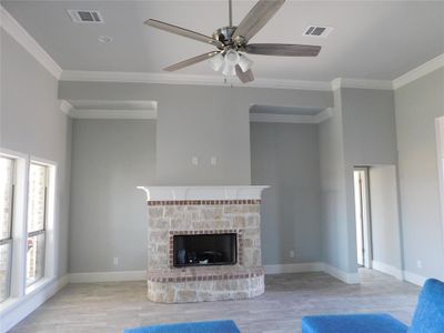 Unfurnished living room featuring a fireplace, light hardwood / wood-style flooring, ceiling fan, and a wealth of natural light