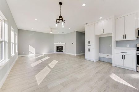 Unfurnished living room featuring a stone fireplace, light hardwood / wood-style flooring, and ceiling fan