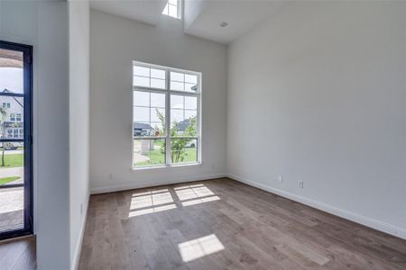 Spare room featuring a towering ceiling and hardwood / wood-style flooring