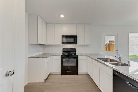 Kitchen featuring light hardwood / wood-style floors, black appliances, sink, and white cabinets