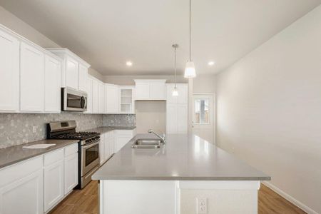 A closer look at the gourmet kitchen with its sleek tile backsplash, abundant cabinetry, and large island with a breakfast bar. Perfect for entertaining or enjoying a quiet morning coffee.