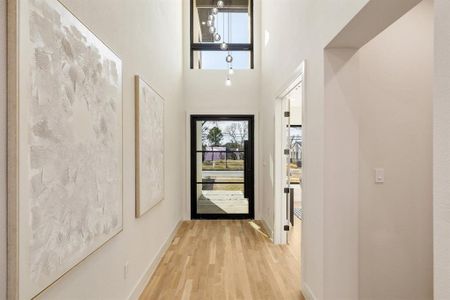 Doorway to outside featuring light hardwood / wood-style floors and a high ceiling