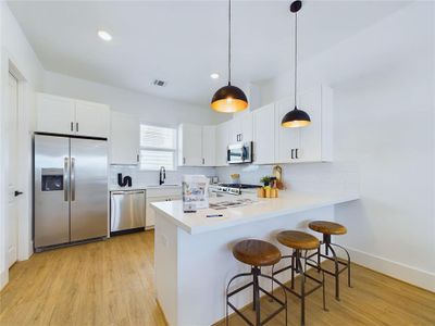 Modern kitchen space is well-lit with natural light and has a minimalist aesthetic.