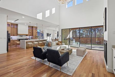 Living room with sink, light wood-type flooring, a high ceiling, and an inviting chandelier