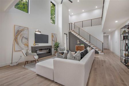 Living room with a high ceiling, ceiling fan, and light hardwood / wood-style flooring