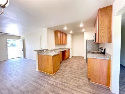 Kitchen featuring light stone counters, sink, kitchen peninsula, light hardwood / wood-style flooring, and stainless steel appliances