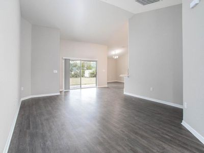 Your living area includes an airy volume ceiling and is finished with luxe wood vinyl plank flooring - New home for sale in Winter Haven, FL