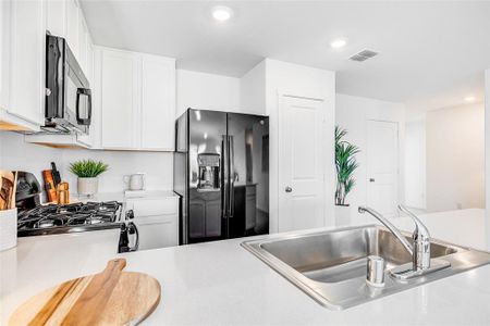 Kitchen with sink, black appliances, and white cabinets