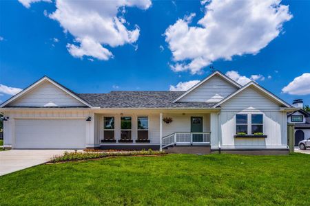 Single story home featuring covered porch, a garage, and a front yard