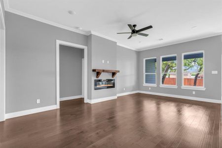 Unfurnished living room featuring ornamental molding, ceiling fan, dark wood-type flooring, and heating unit