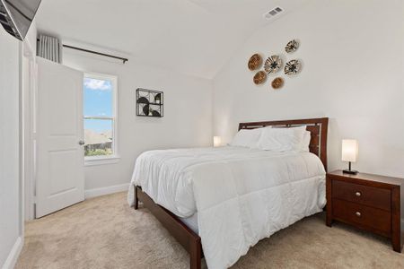 Bedroom with light carpet and lofted ceiling