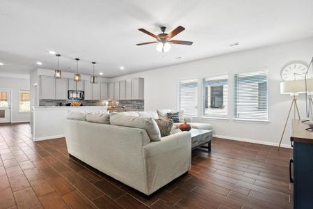 Living room with ceiling fan, a wealth of natural light, and dark hardwood / wood-style floors