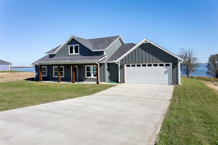 View of front facade with a water view, covered porch, a front yard, and a garage