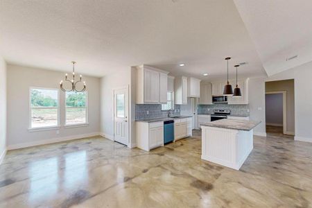 Kitchen featuring white cabinetry, decorative light fixtures, stainless steel appliances, and a kitchen island