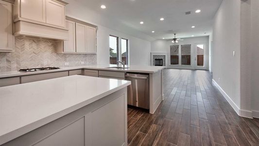 Kitchen featuring dark wood-type flooring, ceiling fan, appliances with stainless steel finishes, decorative backsplash, and sink