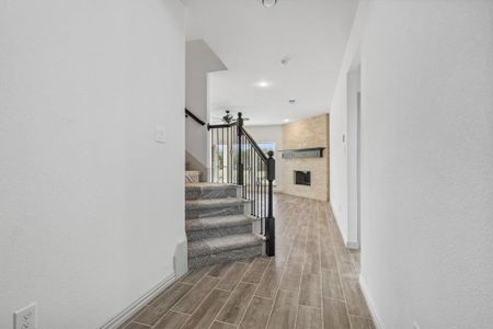 Staircase featuring a fireplace, hardwood / wood-style flooring, and brick wall