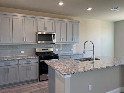 Kitchen featuring appliances with stainless steel finishes, a sink, visible vents, and gray cabinetry