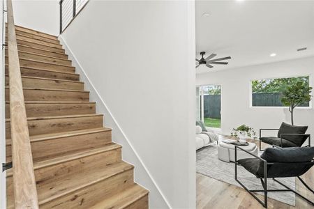 Staircase with ceiling fan and light wood-type flooring