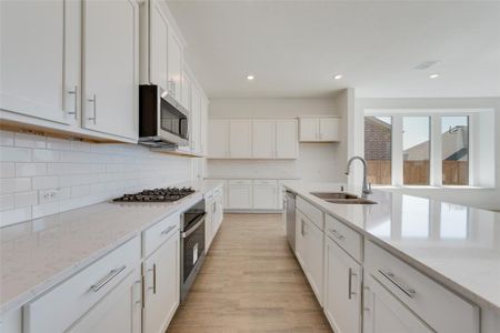 Kitchen with white cabinetry, stainless steel appliances, sink, and light hardwood / wood-style flooring