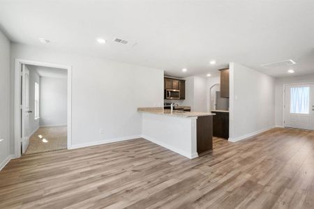 Kitchen with light stone counters, sink, light hardwood / wood-style floors, kitchen peninsula, and appliances with stainless steel finishes