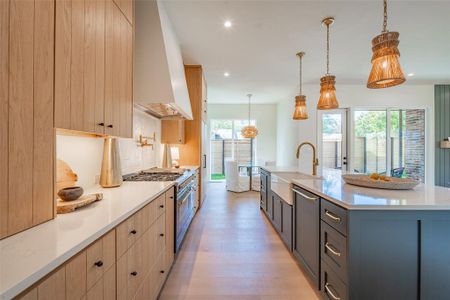 Kitchen with light brown cabinetry, sink, a large island, stainless steel appliances, and pendant lighting