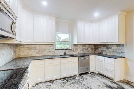 Kitchen with sink, white cabinets, and appliances with stainless steel finishes